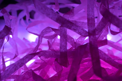 Silk ribbons flowing gracefully in mid-air, illuminated by warm, glowing light particles.