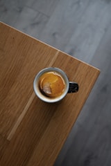 A steaming cup of espresso with crema on top, placed on a rustic wooden table