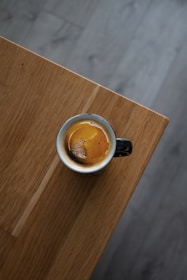 Close-up of a perfectly brewed cup of coffee on a sleek wooden table with minimalist décor