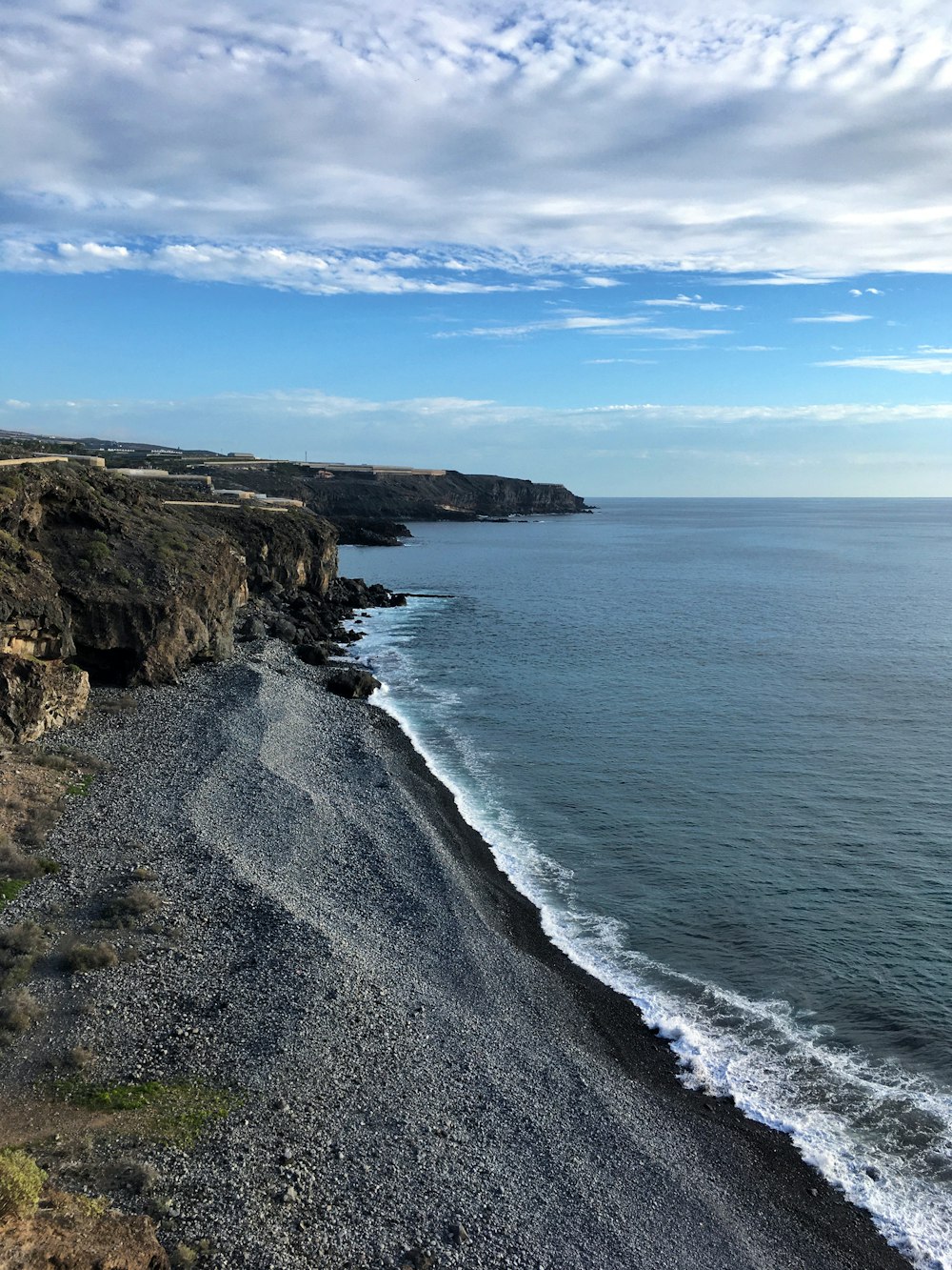 brown rocky mountain beside blue sea under blue sky during daytime