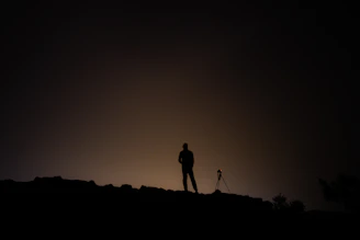 An instructor helping a participant adjust a camera on a tripod under a glowing Milky Way.