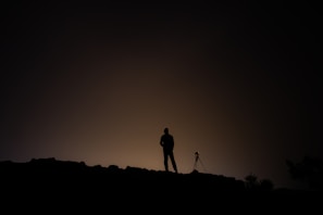A sleek black tripod standing firm on a rocky surface during a sunrise shoot.