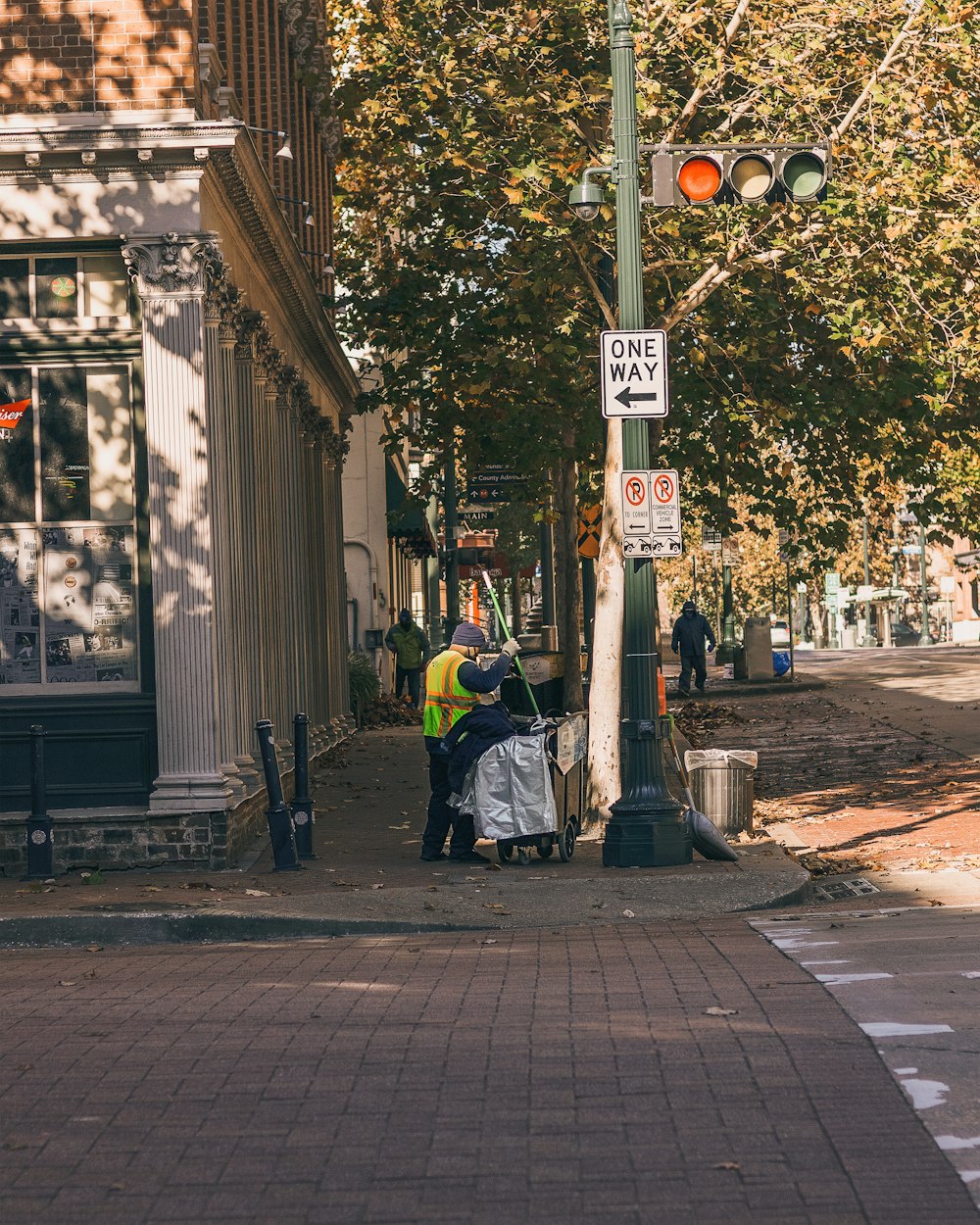 man in yellow jacket and black pants sitting on black steel bench near pedestrian lane during