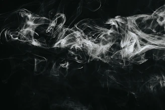 Close-up of flickering black smoke shapes moving fluidly against a shadowy background.