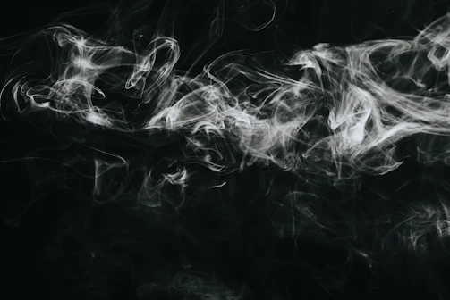Close-up of flickering black smoke shapes moving fluidly against a shadowy background.