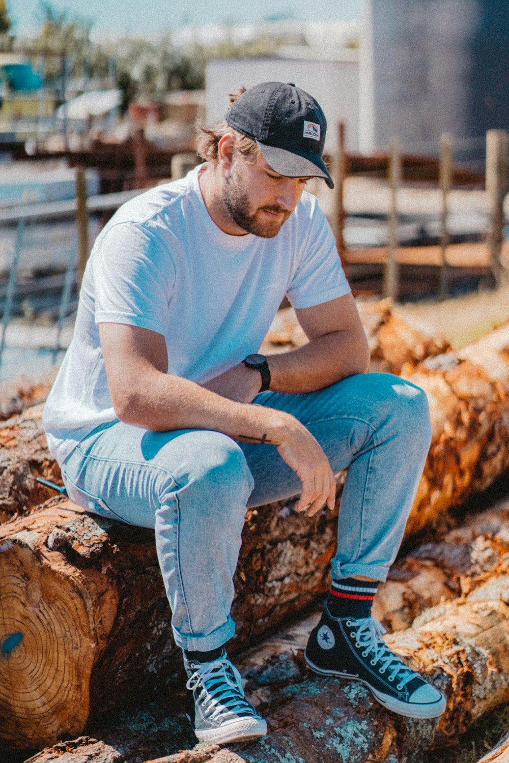 man in blue t-shirt and blue denim jeans sitting on brown wood log during daytime