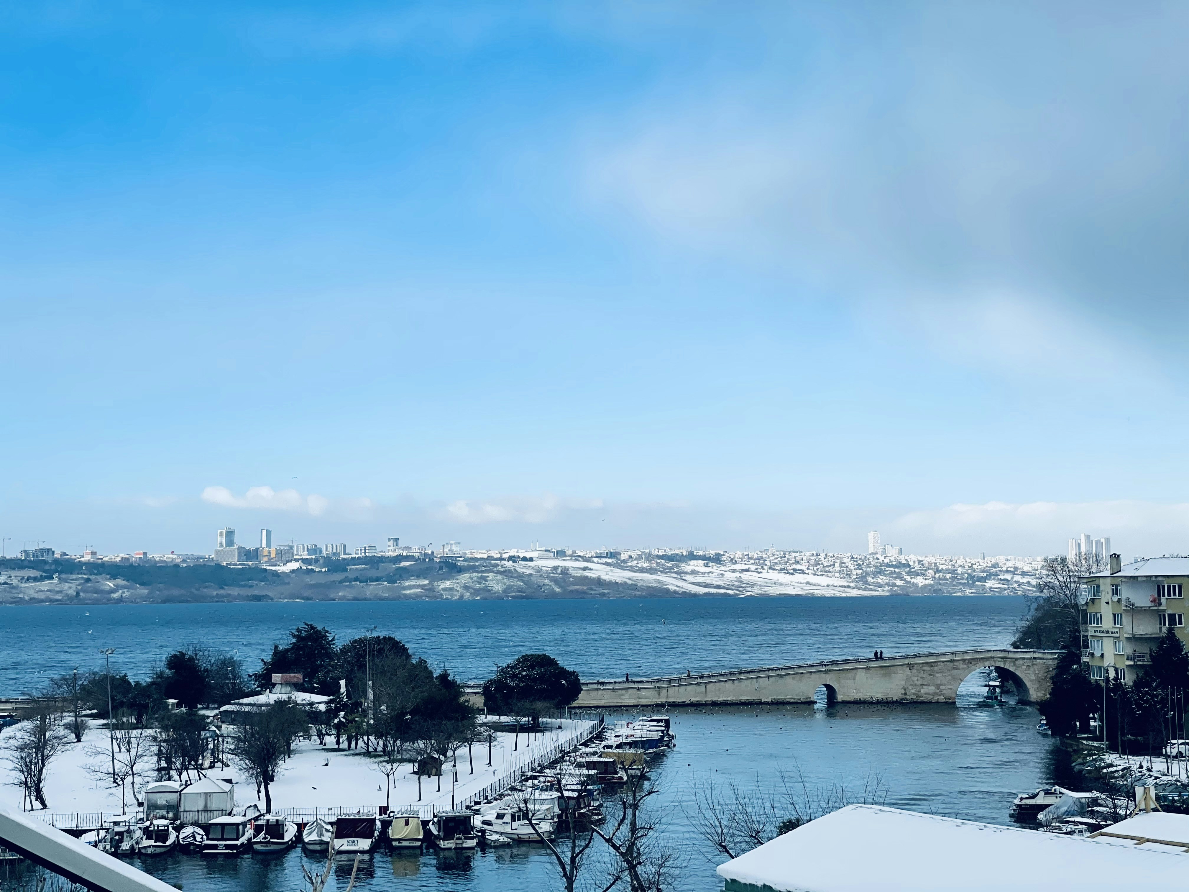 white table and chairs covered with snow near body of water during daytime