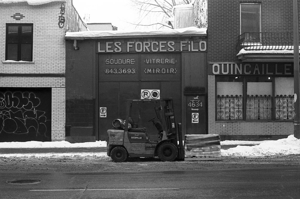 grayscale photo of a truck in front of a building