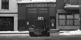 grayscale photo of a truck in front of a building