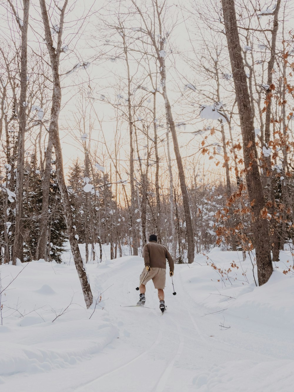 person in gray jacket walking on snow covered ground during daytime