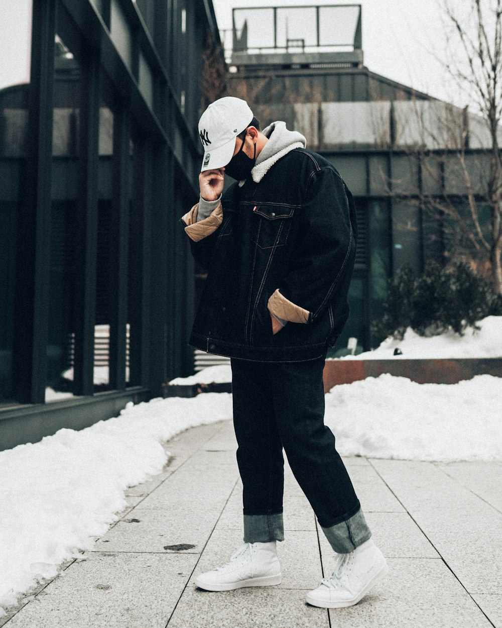 man in black coat and white knit cap standing on snow covered ground during daytime