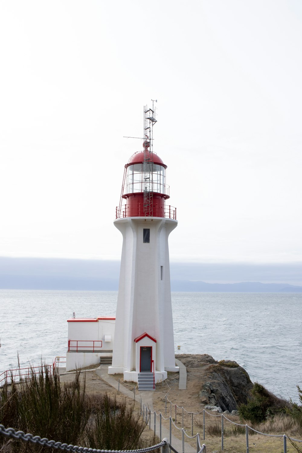 white and red lighthouse near body of water during daytime