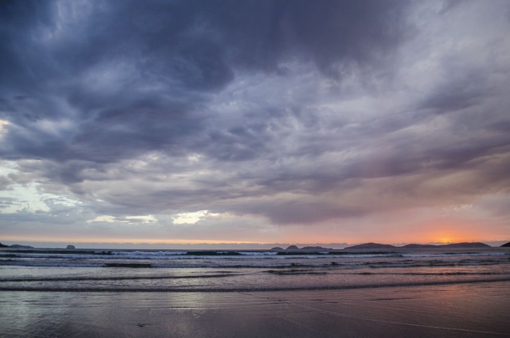 body of water under cloudy sky during sunset