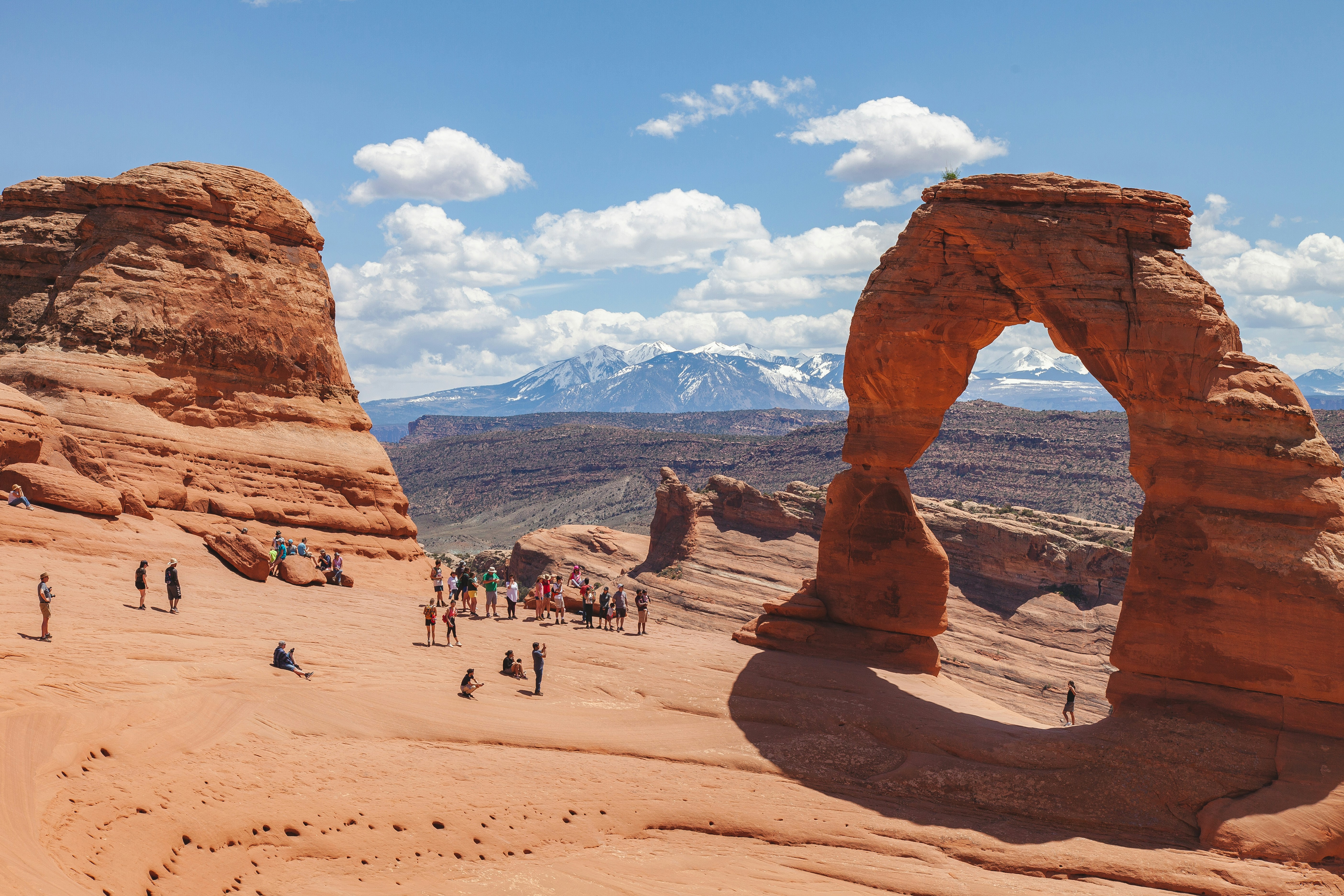 people on beach near brown rock formation during daytime