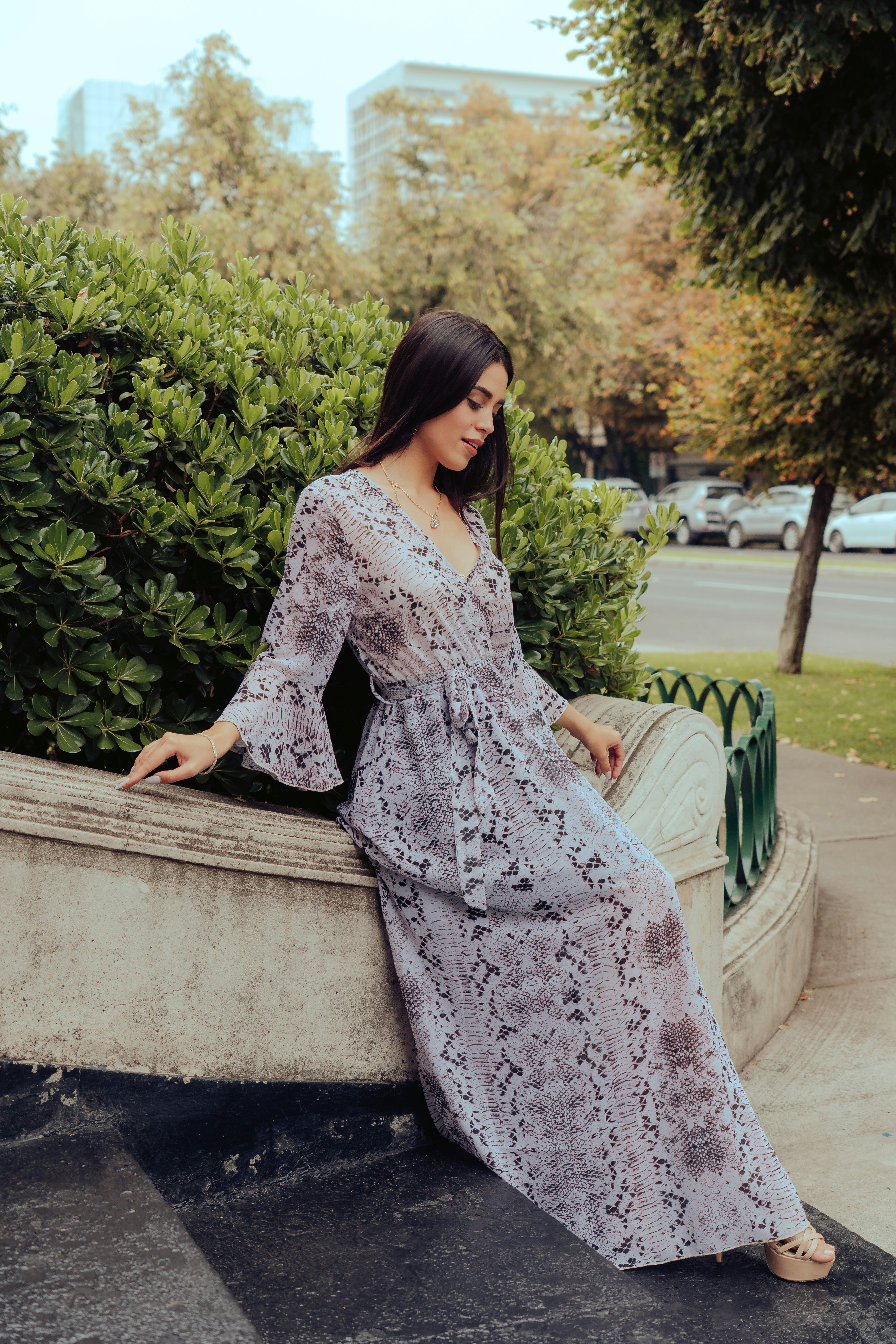 woman in gray floral dress sitting on concrete bench