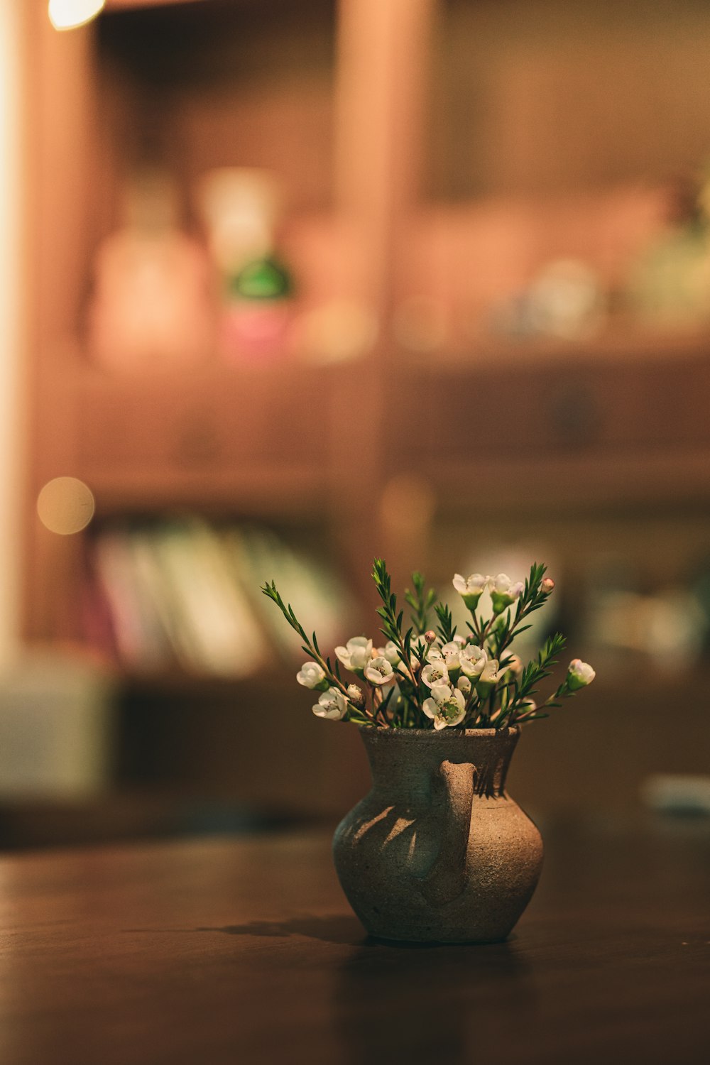 white flowers in brown ceramic vase on brown wooden table
