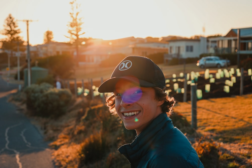 smiling woman in blue hoodie wearing black cap