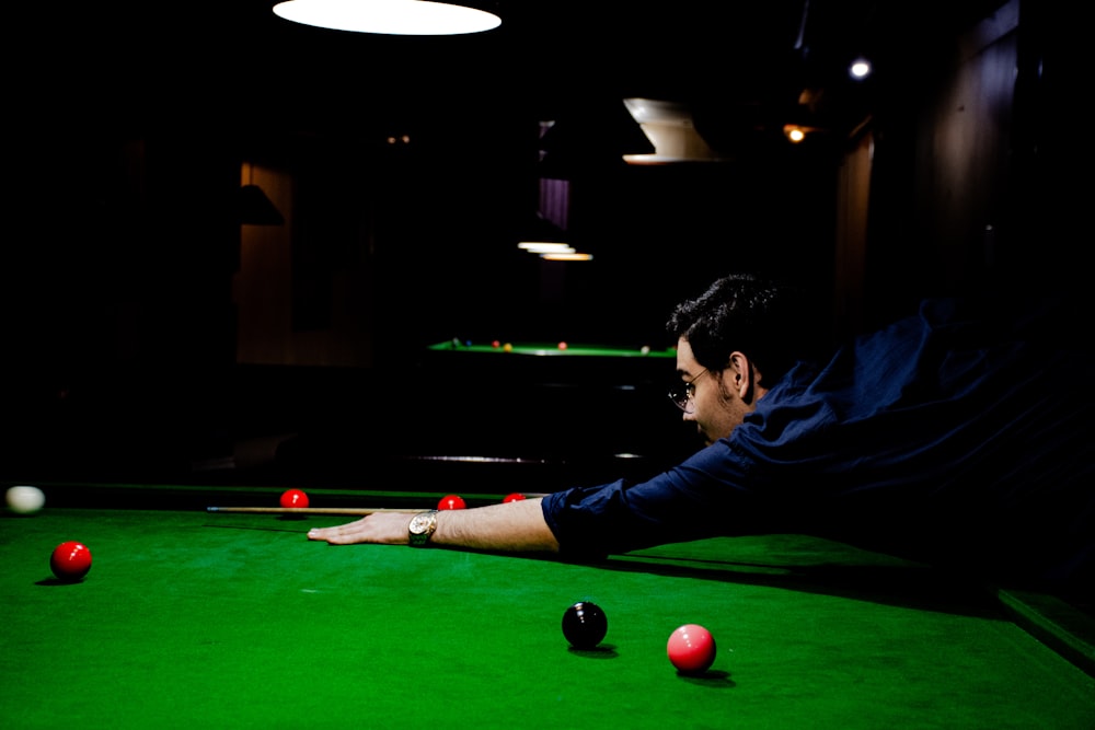 man in blue shirt playing billiard