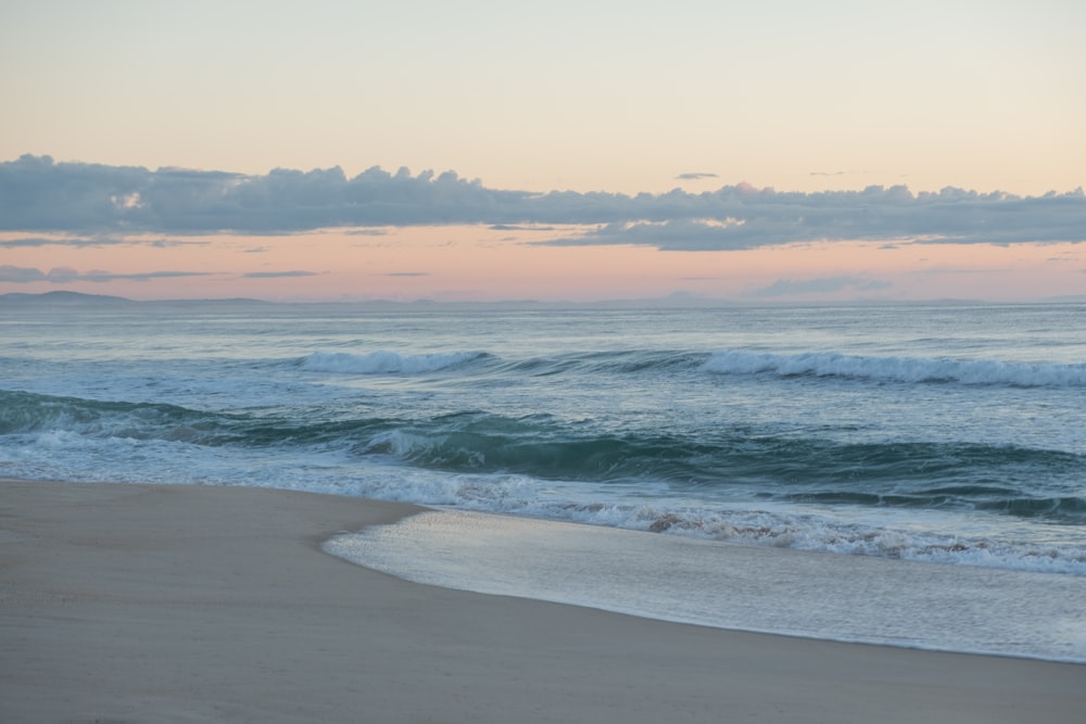 sea waves crashing on shore during sunset