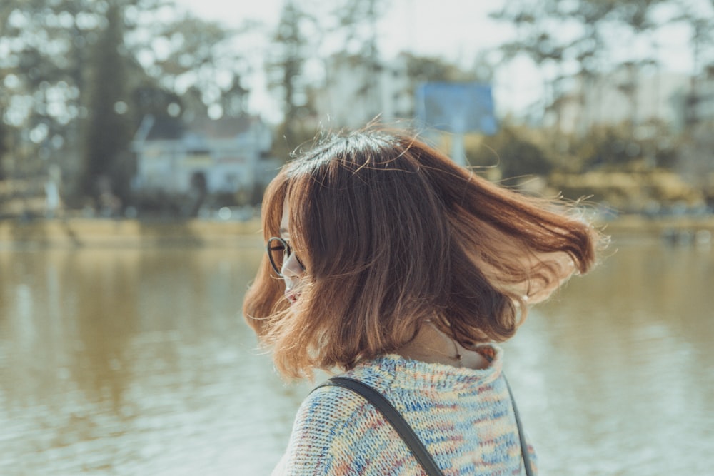 woman in blue and white stripe shirt looking at the river during daytime