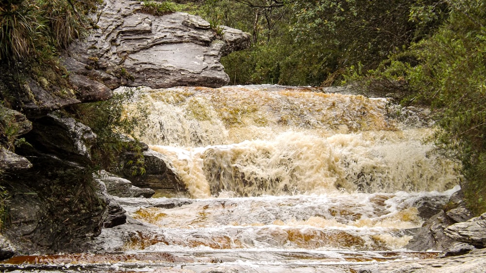 water falls on rocky shore during daytime