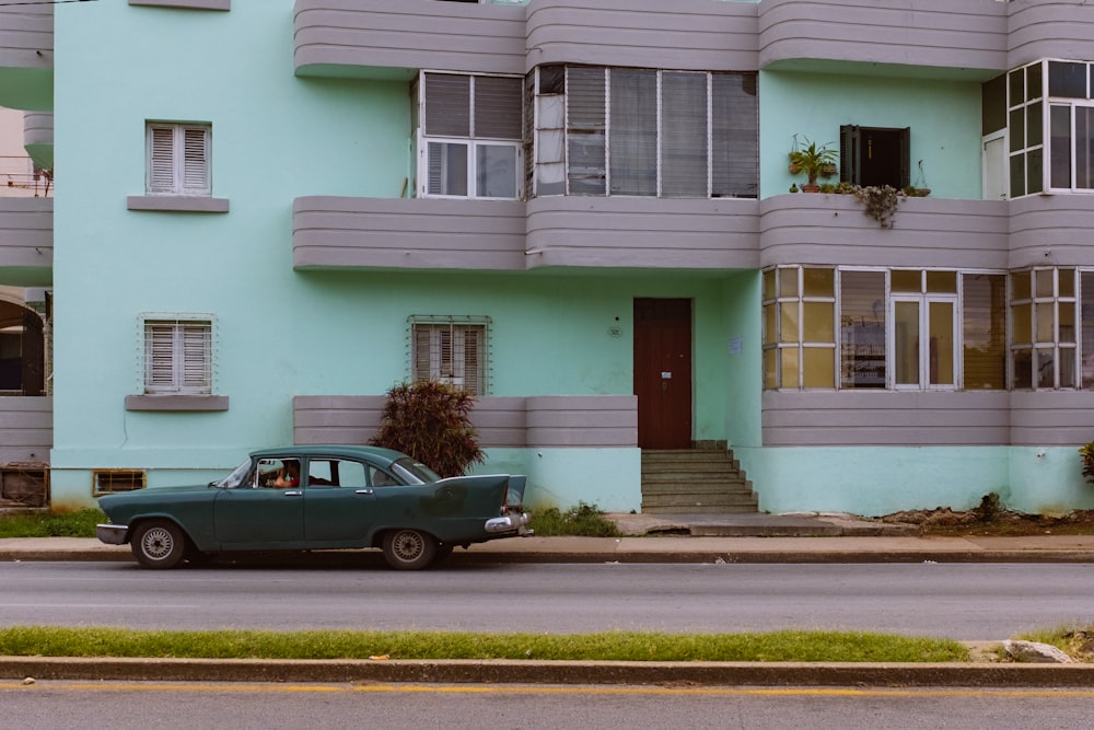 black sedan parked in front of white and pink concrete building during daytime