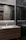 A modern bathroom interior with sleek, dark marble walls and a large mirror that spans the countertop area. The sink is built into a wooden vanity, and there is a chrome faucet. Subtle lighting is embedded above the mirror, casting a soft glow around the room.