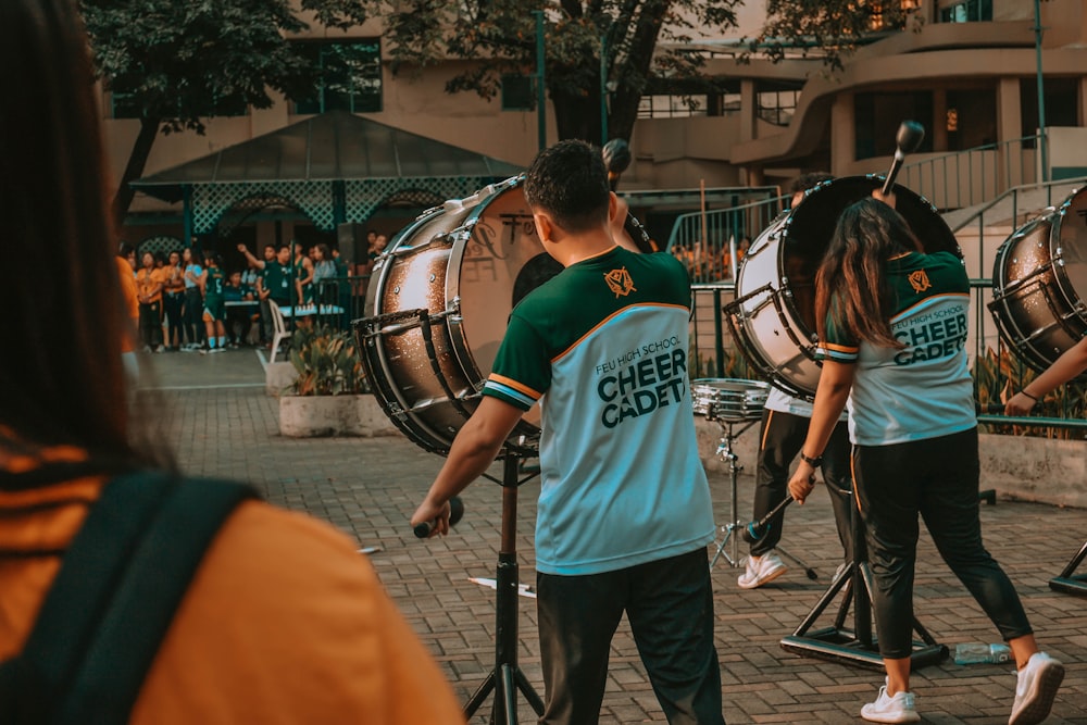 man in green crew neck t-shirt playing drum during daytime