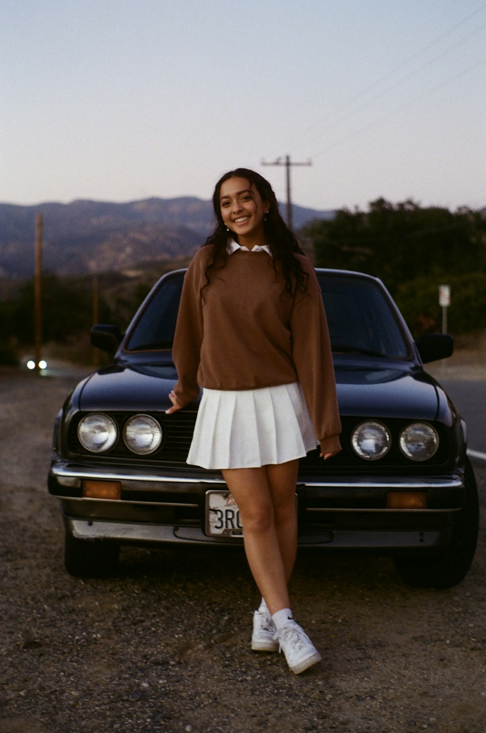 woman in brown long sleeve dress standing beside black car during daytime