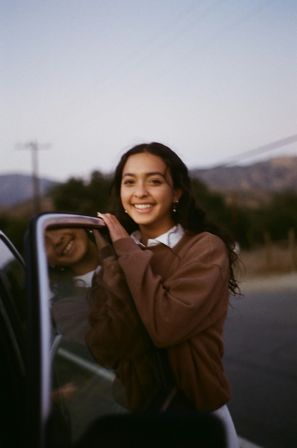 woman in brown coat standing beside car