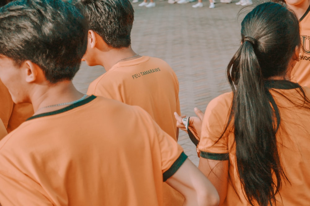 hombre y mujer en camisa naranja de pie junto al cuerpo de agua durante el día