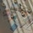 A collection of printed photographs scattered on a textured fabric surface, with rolls of washi tape interspersed among them. The photos show various scenes, mostly nature-related, and are softly lit with shadow patterns cast across them, adding a serene and nostalgic feel.
