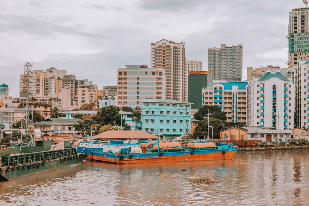 Barca blu e marrone sull'acqua vicino agli edifici della città durante il giorno
