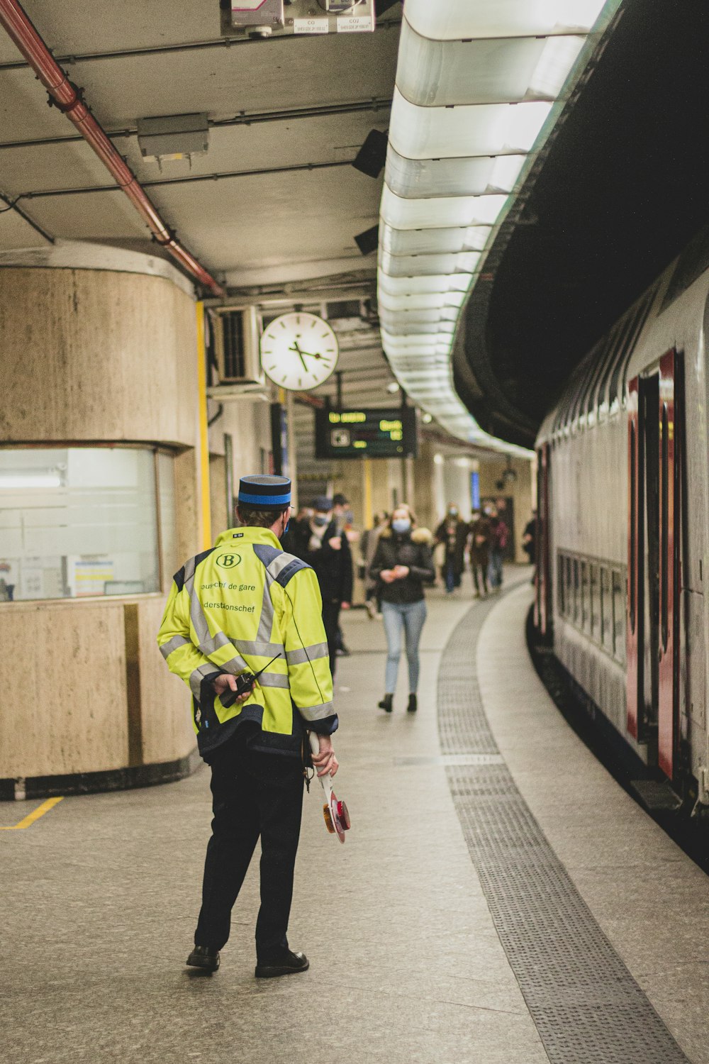 man in green and black jacket walking on train station