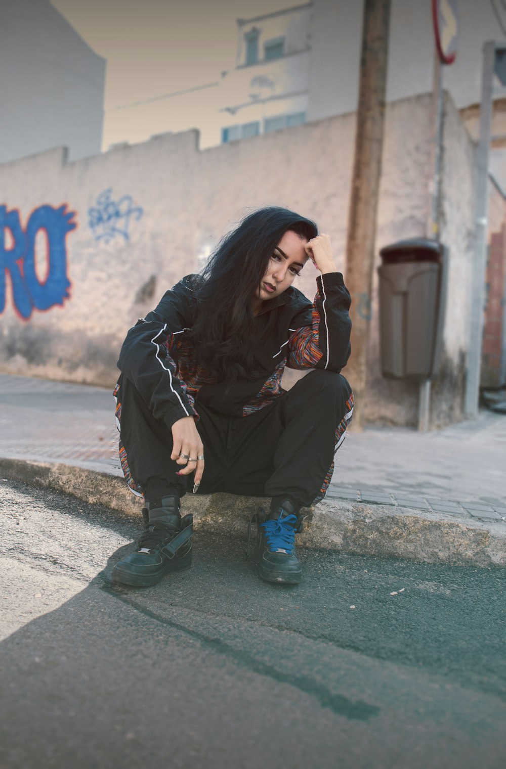 woman in black jacket and black pants sitting on concrete floor