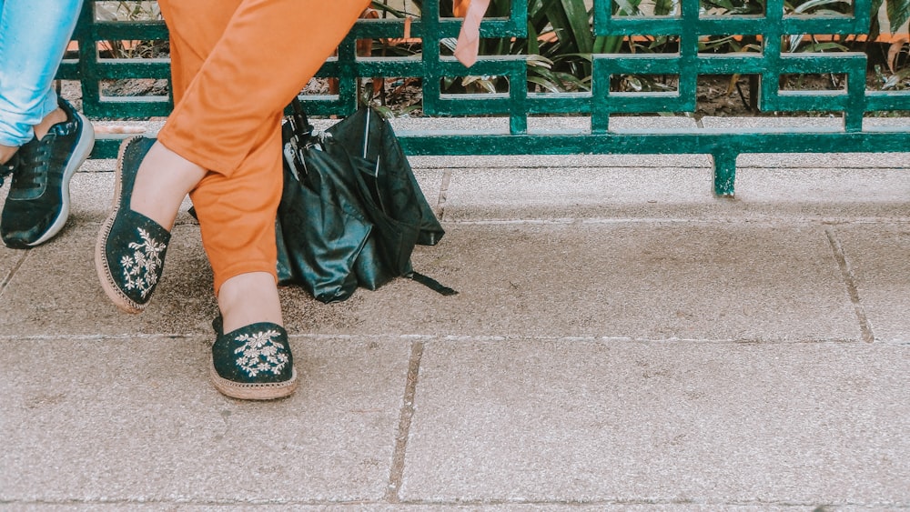 person in orange pants and black leather sandals