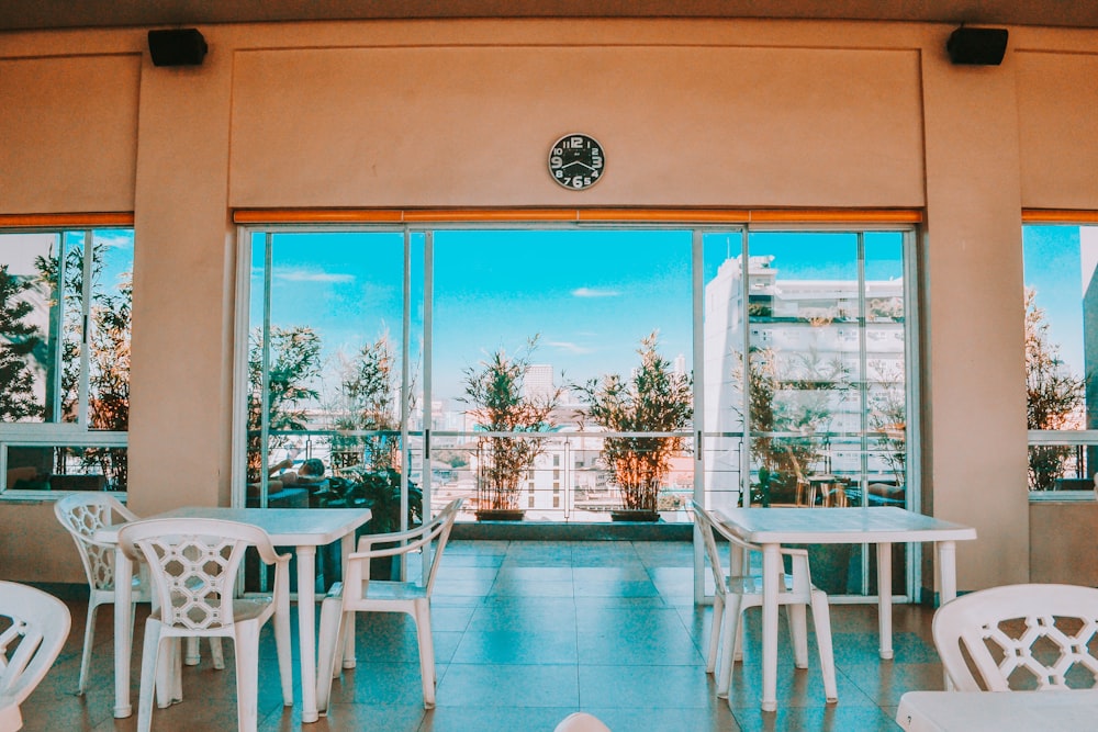 Mesa y sillas de madera blanca cerca de la ventana de vidrio