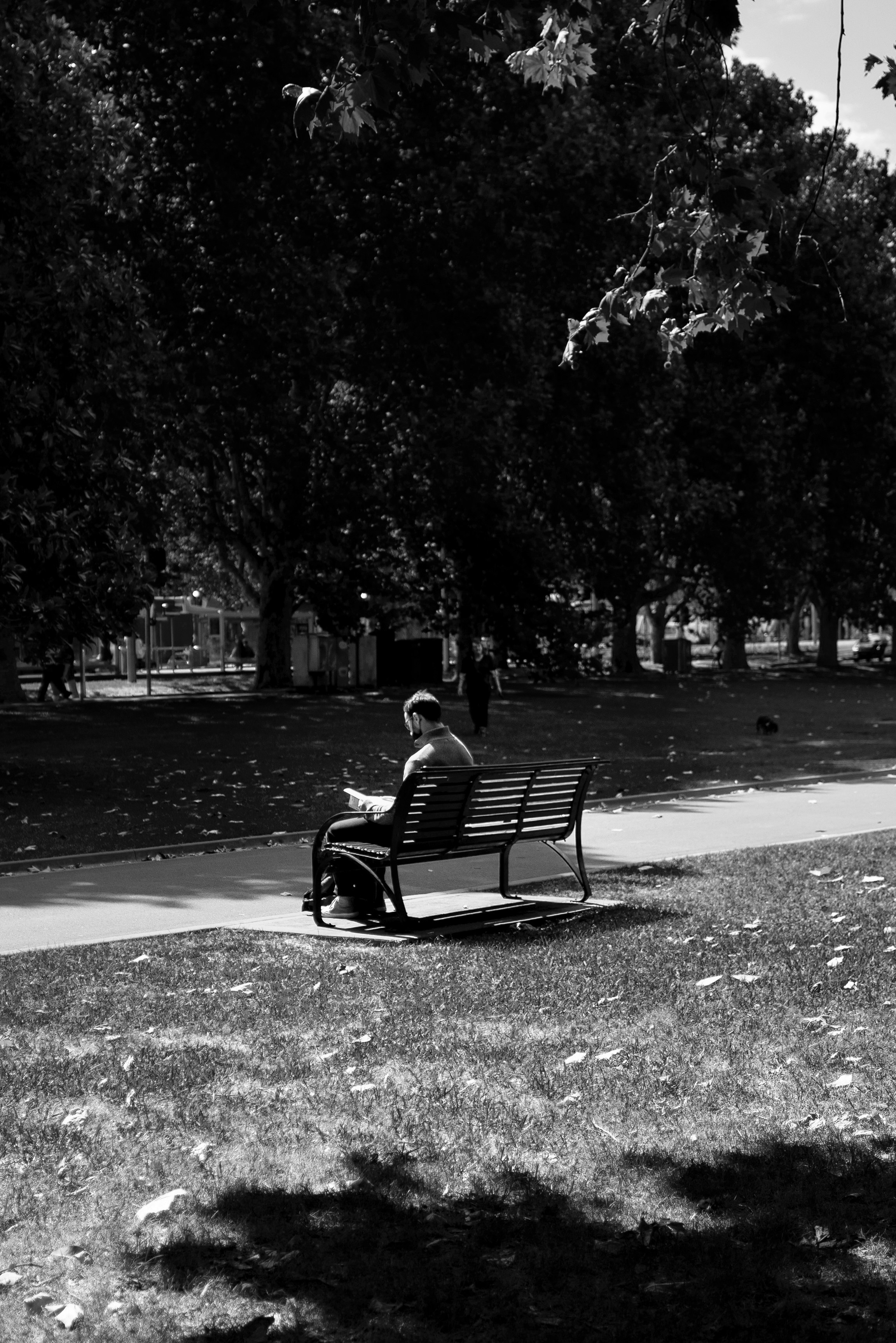 gråtonet foto af person der sidder på bænk