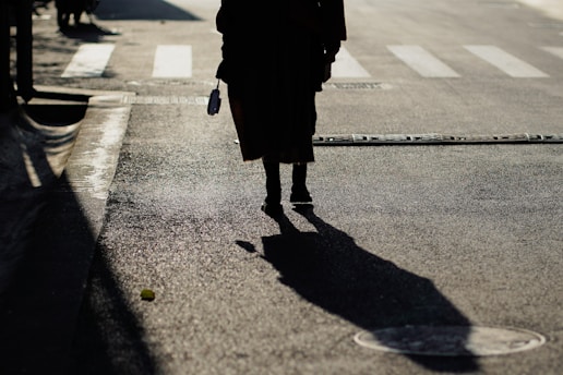 woman in black coat walking on the street during daytime