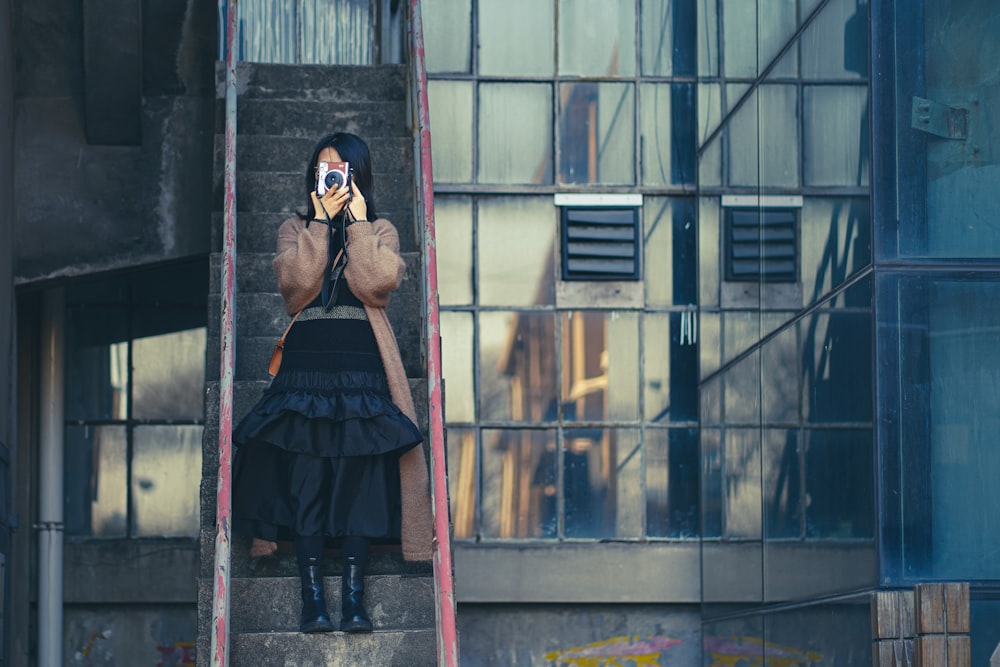 woman in black dress wearing black sunglasses standing in front of window