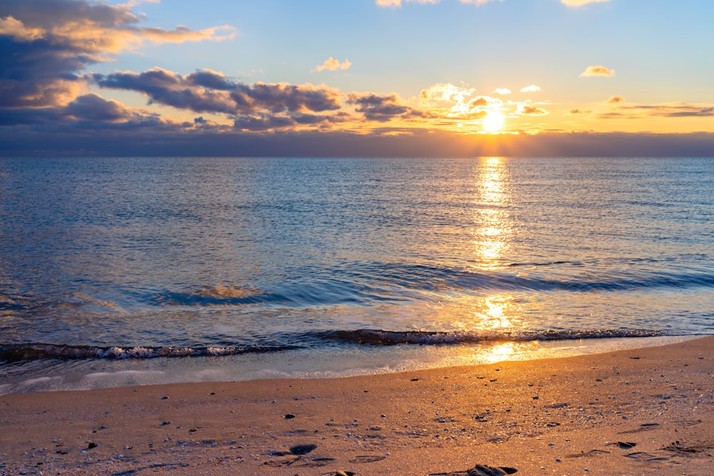 sea waves crashing on shore during sunset