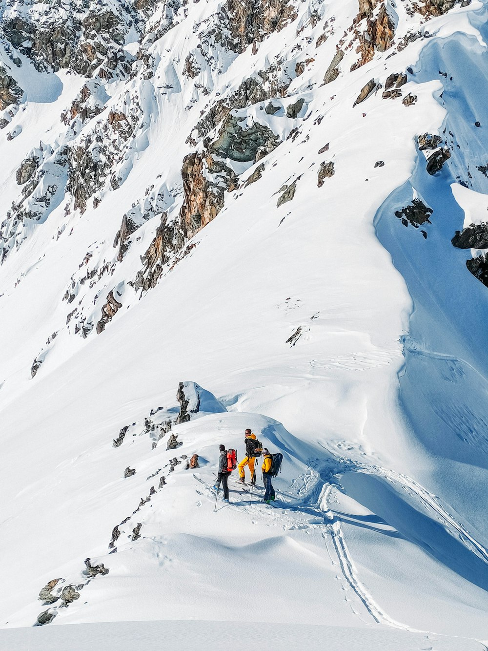 person in black jacket and yellow pants on snow covered mountain during daytime