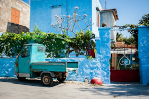 blue car parked beside red and white concrete building during daytime