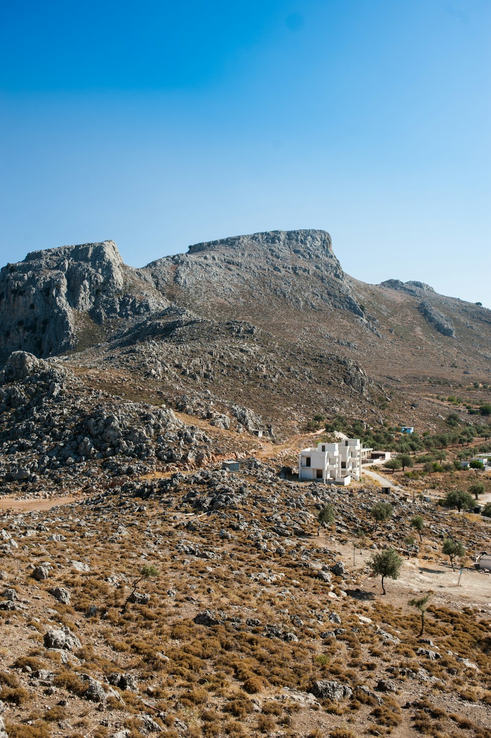 white concrete building near brown mountain under blue sky during daytime