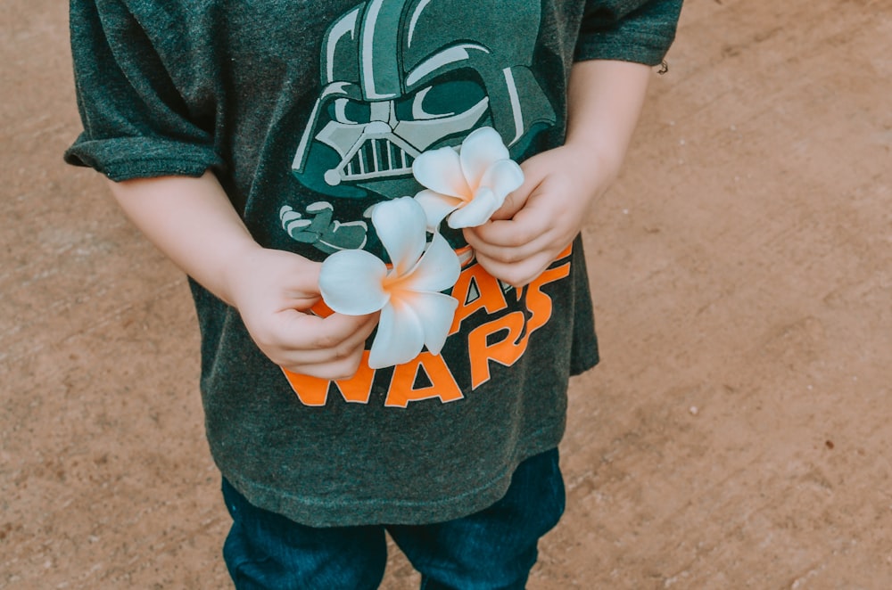 boy in blue and white t-shirt holding white flower