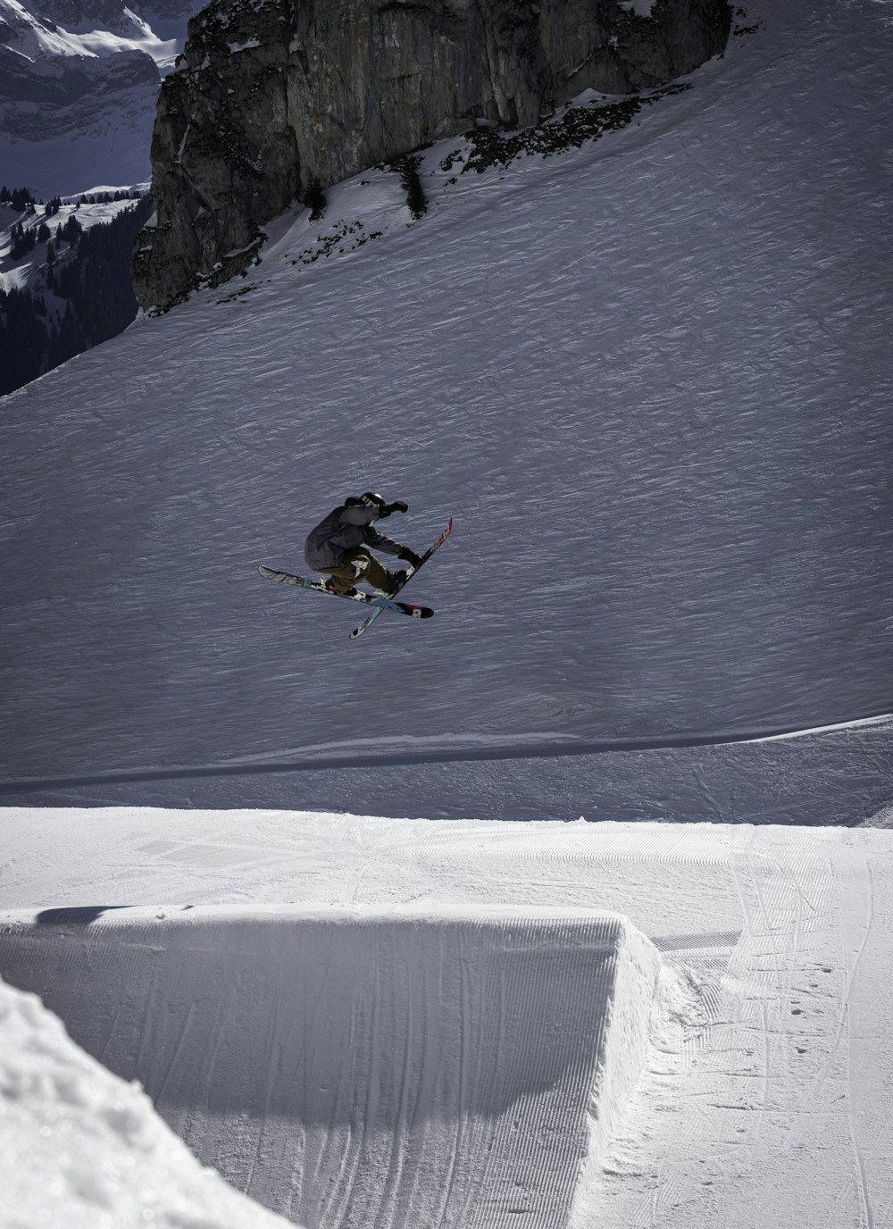 man in black jacket and orange pants riding snowboard on snow covered mountain during daytime