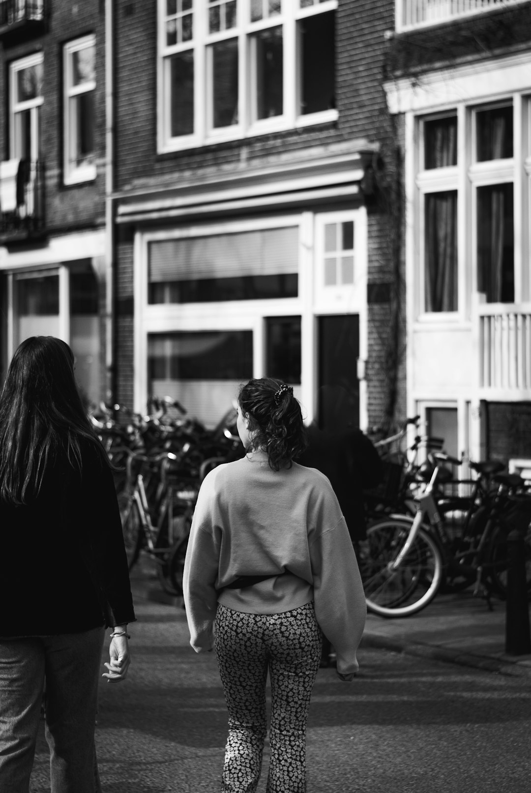 grayscale photo of woman in dress standing on street