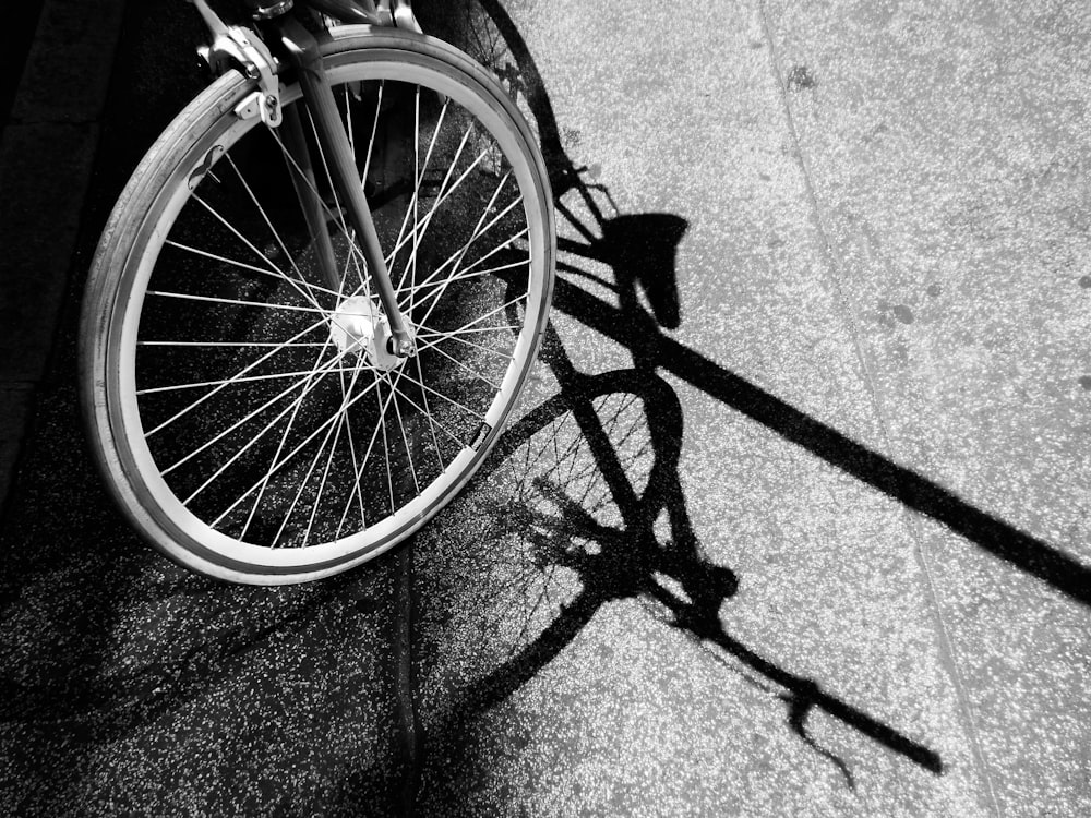 grayscale photo of bicycle wheel on concrete pavement