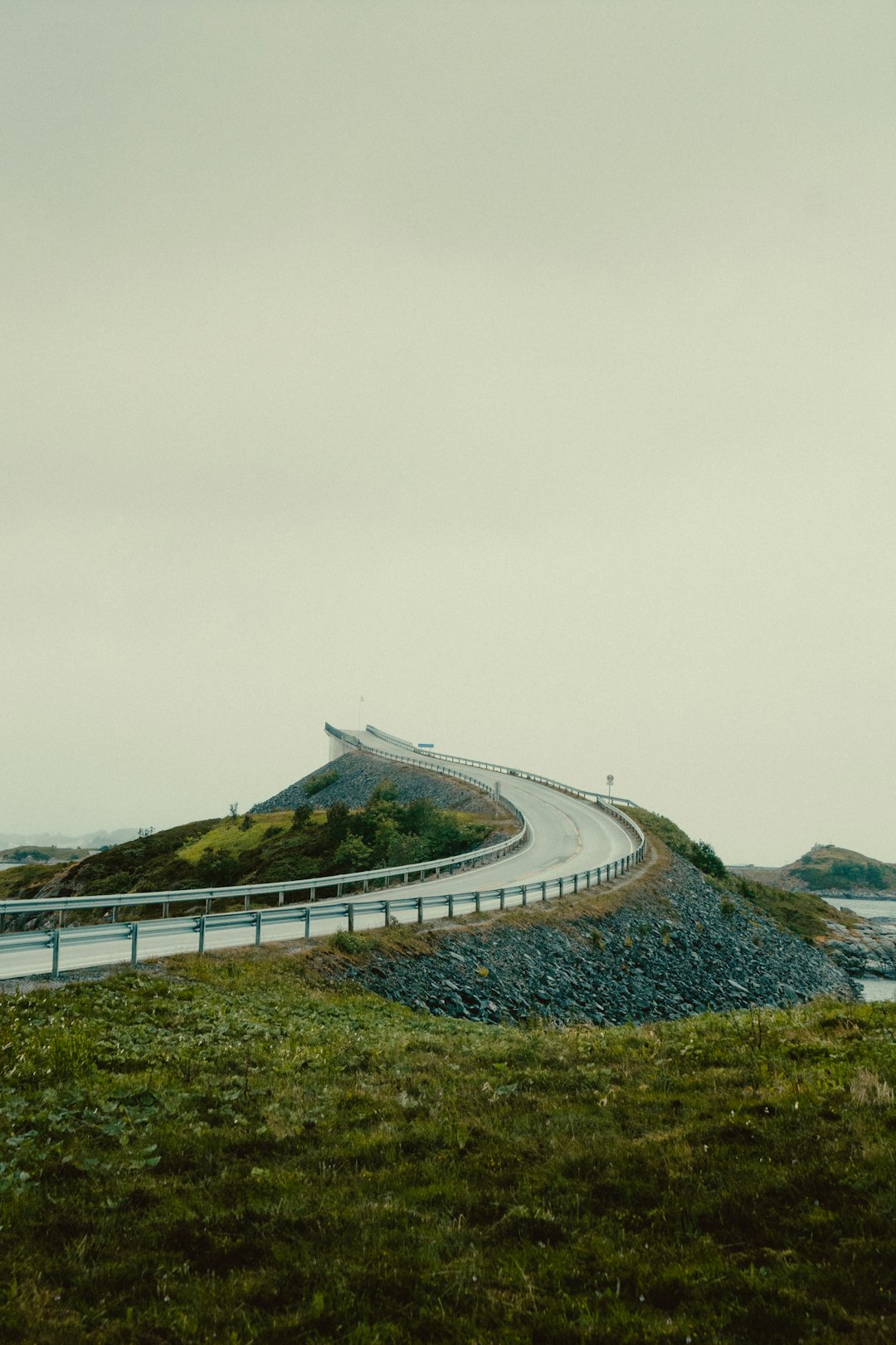 gray concrete road near green grass field under white sky during daytime