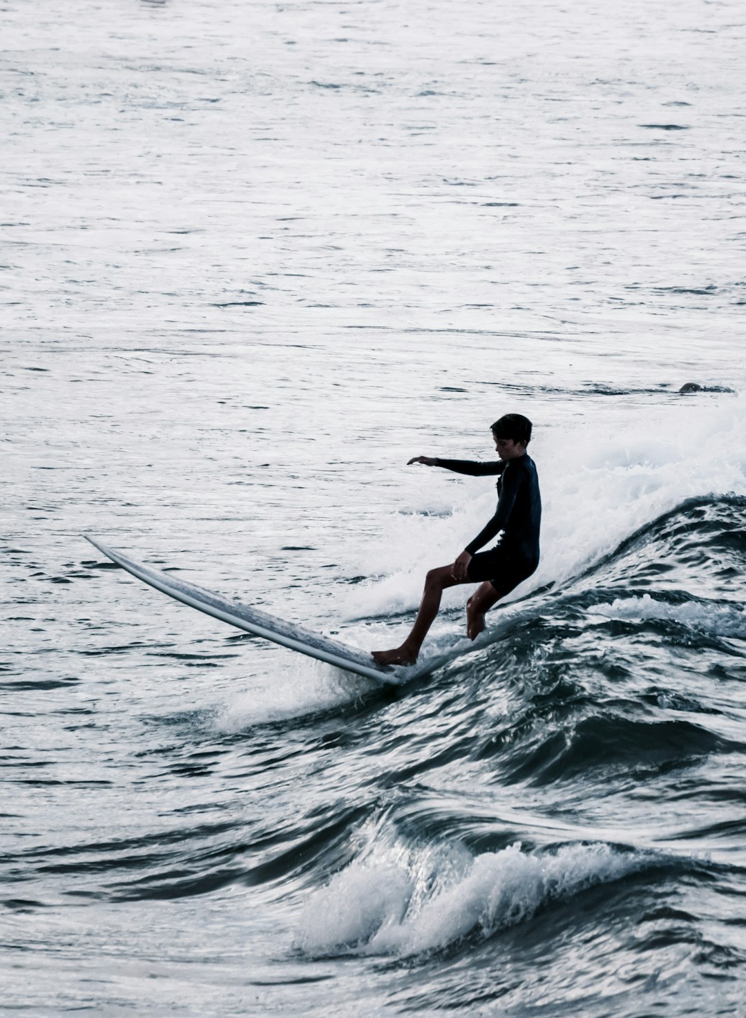 man in black wet suit surfing on sea waves during daytime